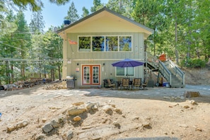 Situated in a forested area, this lodge features a two-story building with a front entrance, outdoor seating area, and staircase.