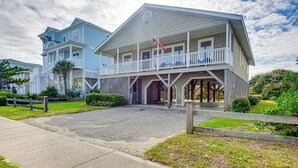 A two-story building with a balcony and a flag. - Home on Ocean Isle Beach w/ Catwalk & Deck (Ocean Isle Beach)