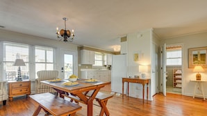 A spacious kitchen with wooden flooring, a dining table with benches, and a chandelier. - Home on Ocean Isle Beach w/ Catwalk & Deck (Ocean Isle Beach)