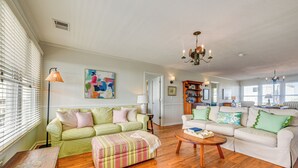 A spacious living room with a green and white checkered sofa, a white sofa with green pillows, and a wooden coffee table. - Home on Ocean Isle Beach w/ Catwalk & Deck (Ocean Isle Beach)