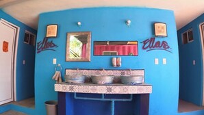 Une salle de bain avec un mur bleu, un lavabo avec des cuves en métal et un miroir.