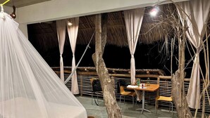 A tented outdoor area with a dining table and chairs, surrounded by trees and a thatched roof structure. - New Amazing room in a Tree house at a superb bay! (Arroyo Cruz)