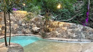 A swimming pool with a stone wall and a concrete deck. - New Amazing room in a Tree house at a superb bay! (Arroyo Cruz)