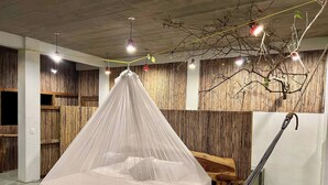 A bed with a canopy in a room with wooden walls and hanging lights. - New Amazing room in a Tree house at a superb bay! (Arroyo Cruz)