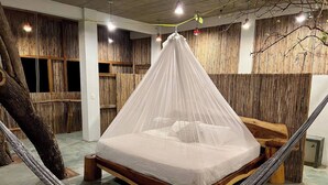 A hammock bed with a canopy in a room with wooden walls and a concrete floor. - New Amazing room in a Tree house at a superb bay! (Arroyo Cruz)