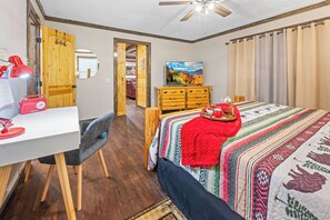 Une chambre à coucher comprenant un lit, un bureau, une chaise, une commode et un ventilateur de plafond.