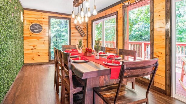A wooden dining room with a large table set for six, surrounded by chairs. - Cozy Family Cabin in charming Smoky Mountain- Pets allowed  (Cosby)