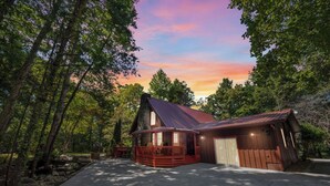 A cabin with a large porch, a garage, and a covered outdoor area, surrounded by trees. - Cozy Family Cabin in charming Smoky Mountain- Pets allowed  (Cosby)