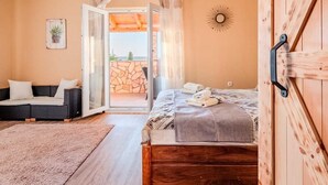 A bedroom with a wooden bed, a sofa, a view through a glass door, and a wooden wall. - Villa Badi with private pool (Malinska (Krk))