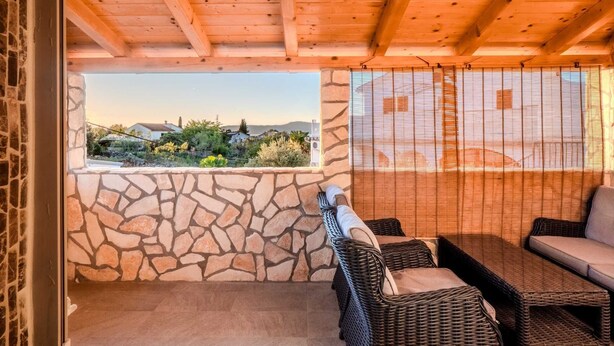 A covered outdoor seating area with stone walls and wicker furniture. - Villa Badi with private pool (Malinska (Krk))