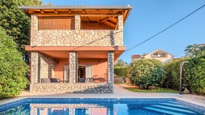A two-story house with a stone facade, a swimming pool in front, and a patio area with outdoor furniture. - Villa Badi with private pool (Malinska (Krk))