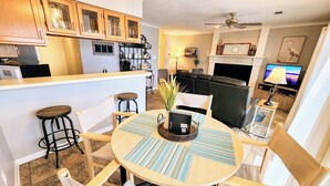 A modern kitchen with wooden cabinets, a bar area, and a dining space with a round table and chairs. - Farr Shores Cozy Retreat (Hot Springs)