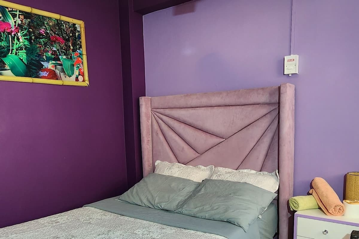 A bedroom with a bed, a nightstand, a ceiling fan, and a wall-mounted light fixture.