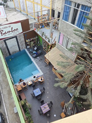 A rooftop pool area with lounge chairs and tables, surrounded by potted plants and a bamboo structure. - La casa de Bamboo (Ica)