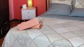 Une chambre à coucher comprenant un lit, une table de chevet, un ventilateur de plafond, une armoire et une prise électrique murale.