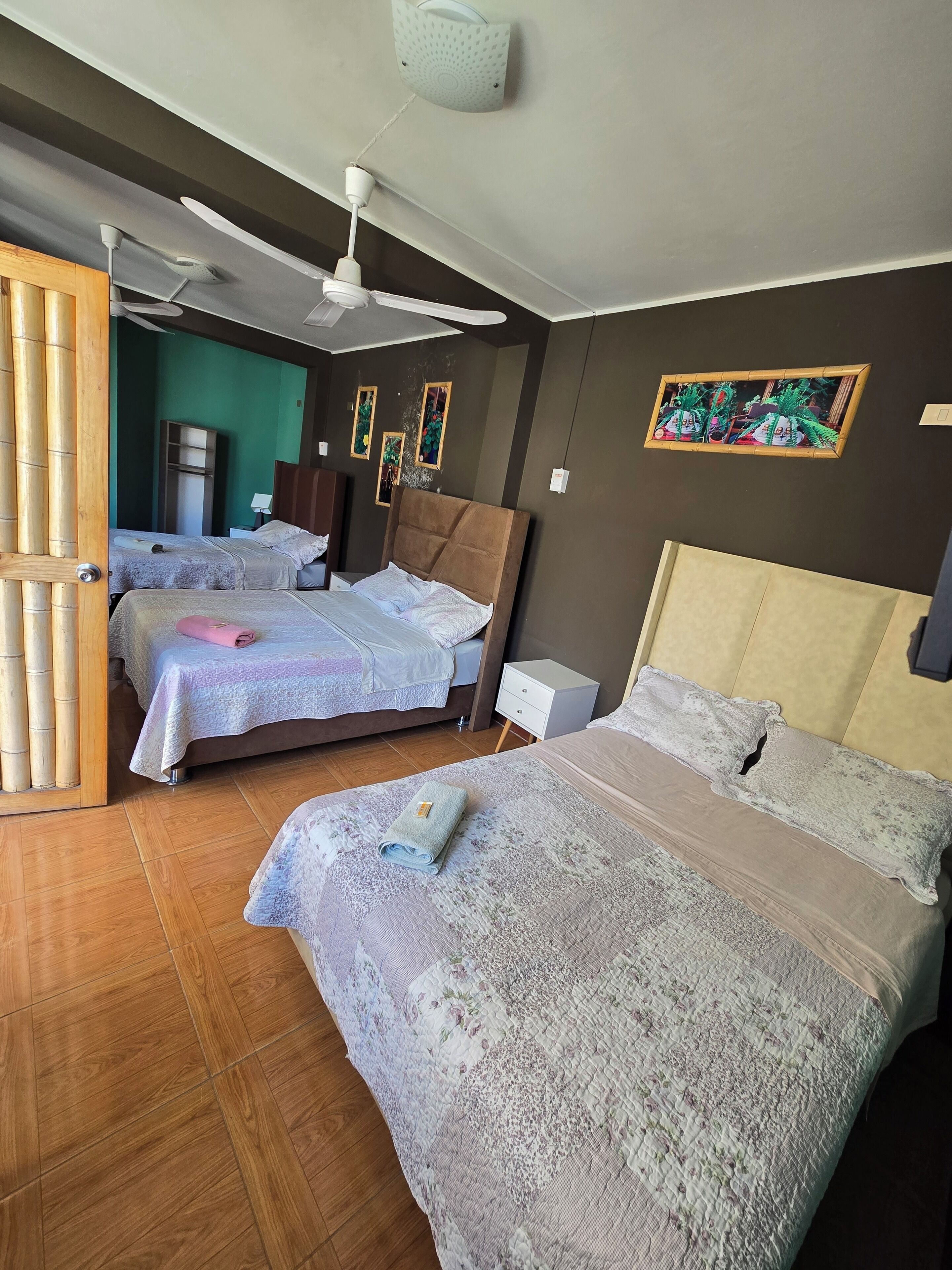 Habitación de hotel con dos camas, ventilador de techo, purificador de aire montado en la pared y una puerta de madera.