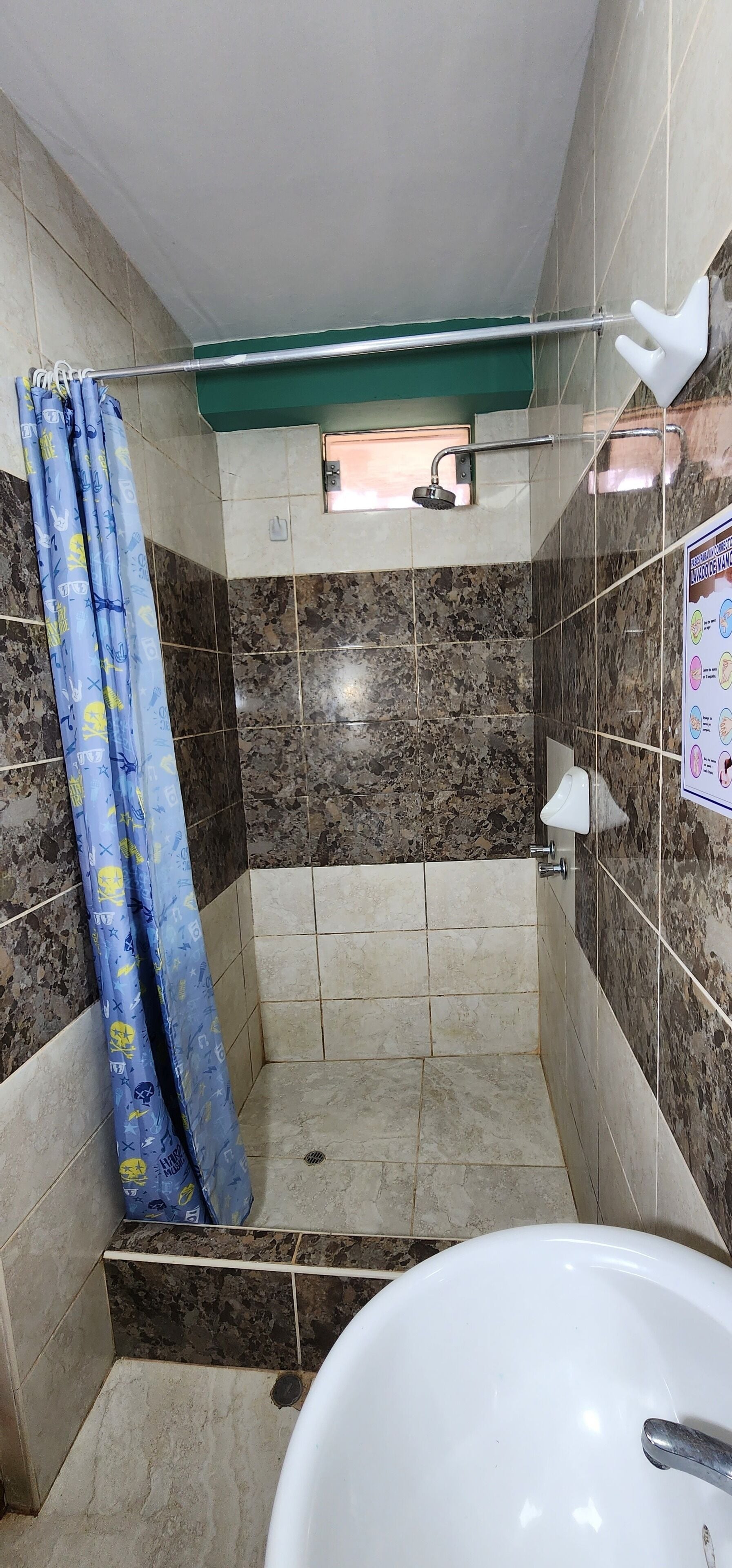 A small bathroom with a shower, a white sink, and a blue shower curtain.