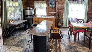 A rustic cabin interior with a kitchen, dining area, and bar stools.