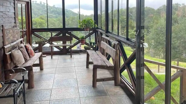 A covered outdoor seating area with wooden benches and a view of a mountainous landscape.
