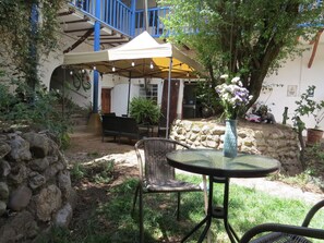 An outdoor patio with a round table and two wicker chairs, a covered seating area with a yellow canopy, and a stone wall. - Colonial House with 5 Private Rooms, 2 Blocks from Main Square (Cusco)