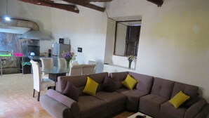 Una sala de estar con un sofá modular, una mesita con un florero y una cocina al fondo.