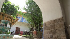Un patio exterior con pared de piedra, barandilla azul y plantas en macetas.