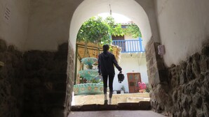 Un estrecho pasaje que conduce a un patio interior, con una persona caminando hacia un edificio.