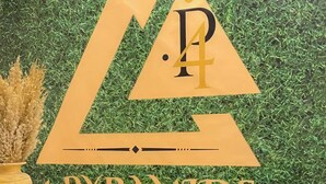Uma mesa de recepção com um logotipo e o nome '4 Pyramids' ao fundo esverdeado.