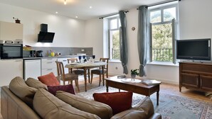 A modern living room with a sofa, a dining table, and a TV.