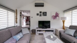 Ein modernes Wohnzimmer mit grauem Sofa, Couchtisch, Fernseher und Bildern an der Wand.