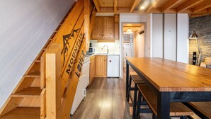 Une cuisine moderne avec des meubles en bois, un four encastré et un coin repas comprenant une table et des bancs en bois.