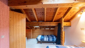 Une cabane en bois avec deux lits, un plafond en bois et une petite fenêtre.