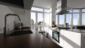 A modern kitchen with a large island, stainless steel appliances, and a view of the city through large windows. - Seaviews-gijon-parking-2br-walk to Beach-wifi (Gijon)