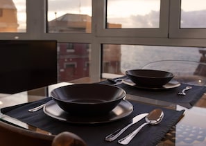 A dining table with two dark bowls, a knife, and a spoon on black placemats.