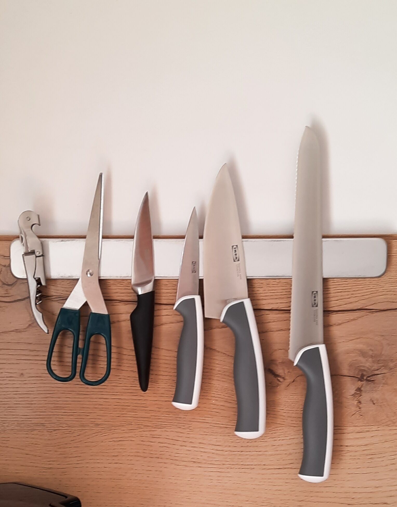 A kitchen counter with various kitchen utensils and tools, including scissors, a knife, and a can opener.