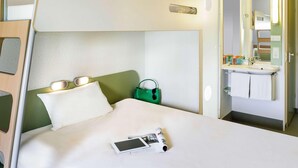 A bunk bed with a bedside table, a green bag, and a tablet on the bed. - B&B Hotel Berlin Genshagen-nord (Ludwigsfelde)
