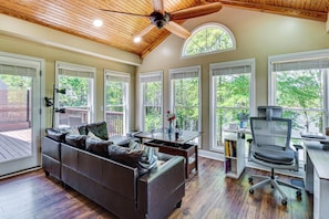 A spacious living room with a wooden ceiling, a leather sofa, a dining table, and a computer desk with a chair. - Lakefront Escape w/ Dock & Fire Pit: Sleeps 12 (Murrayville)