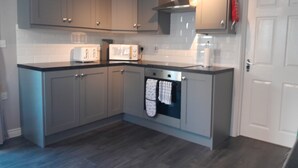A kitchen with grey cabinets, a microwave, a toaster, and a stove. - Tranquil Retreat Close to the Coast (Coleraine)