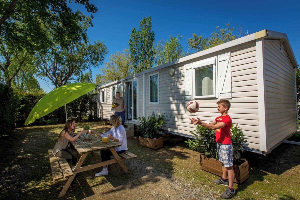 A mobile home with a patio area, a picnic table, and potted plants.
