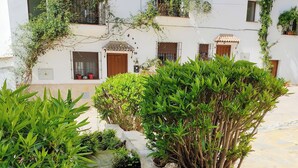 A courtyard with a small stream, surrounded by lush greenery and white buildings with balconies. - Beautiful views of the Sierra de Grazalema, ideal to enjoy and disconnect. (Montecorto)
