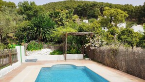 A rectangular swimming pool with a tiled edge, surrounded by a wooden fence and lush greenery, including a pergola with flowering plants. - Beautiful views of the Sierra de Grazalema, ideal to enjoy and disconnect. (Montecorto)