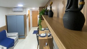A modern dining area with a wooden table set for two, a blue sofa, and a decorative black sculpture. - Villas do Porto - 312 by La Playa (Ipojuca)