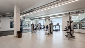 Un gimnasio amplio con diversas máquinas de ejercicio, ventanas grandes y un diseño moderno y limpio.