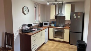 A compact kitchen with a microwave, stove, sink, and a refrigerator. - Cozy City Centre 1-bed Apt, 1 Bath, (Coventry)