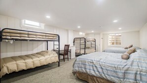 Une chambre de type dortoir, avec des lits superposés, un bureau et une chaise.