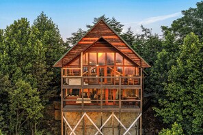 A multi-level wooden cabin with large windows, surrounded by dense forest. - Best Views in Sevierville! 1b/2ba + Loft! Hot Tub. 15 min to Pigeon Forge! (Sevierville)
