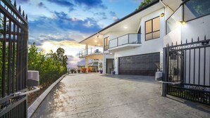 A modern two-story house with a covered driveway, a garage, and a gated entrance. - Your Ultimate Escape in Mooroobool- Luxury Tropical Retreat with Pool & Stunning Views – Perfect for Families & Groups! (Mooroobool)