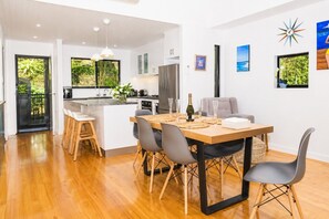 A modern kitchen with a central island, wooden flooring, and a dining area with a table set for four.