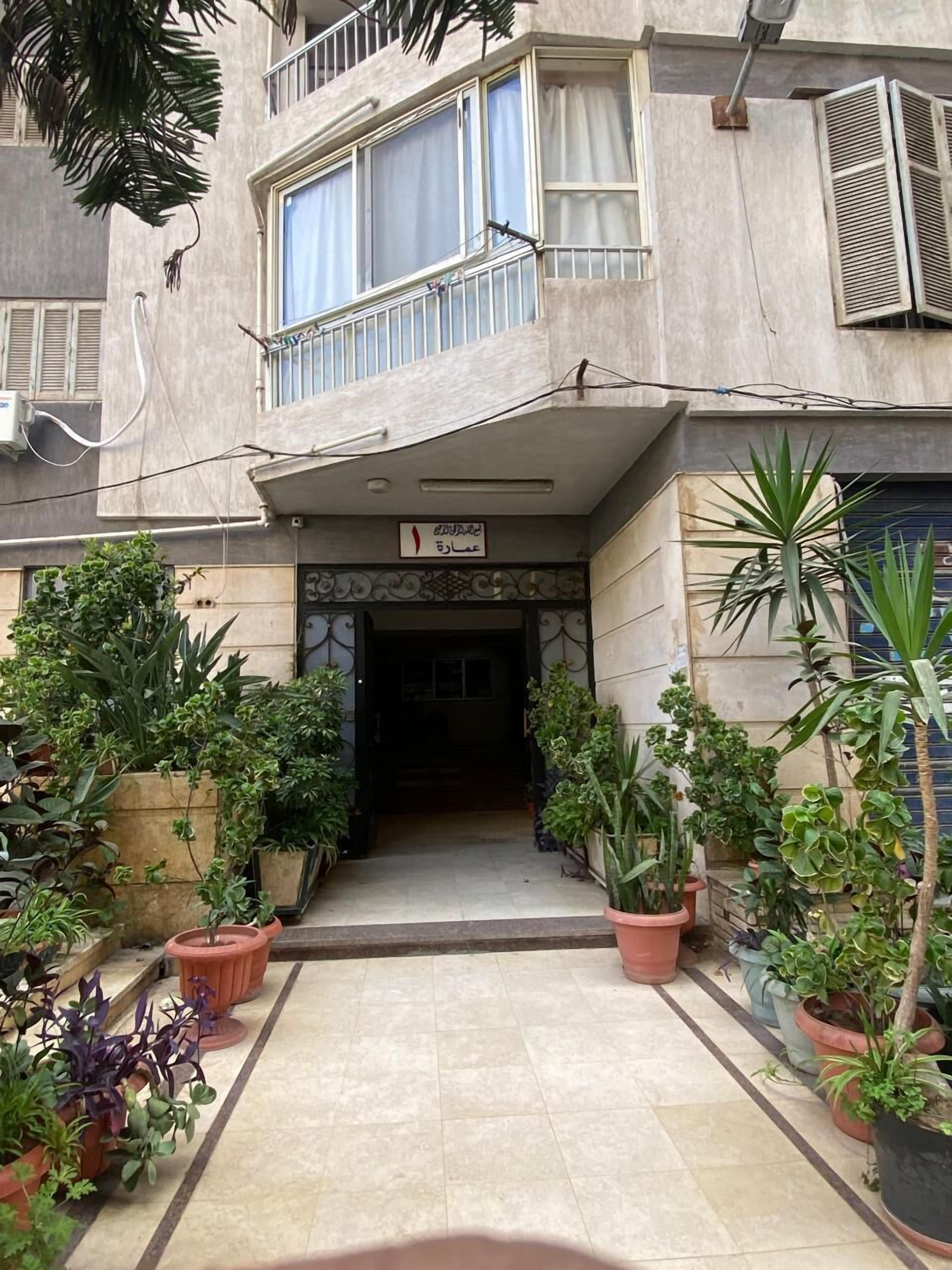 A building with a tiled entrance, potted plants, and a sign above the door.