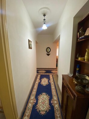 Ein Flur mit Teppichmuster, Deckenventilator und Wandspiegel.